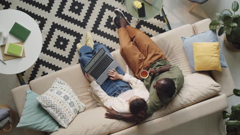 Couple-Using-Laptop-and-Talking-on-Sofa-at-Home