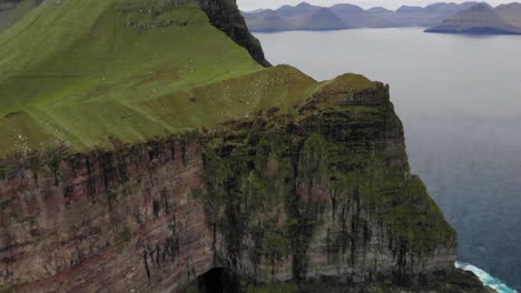 4k aerial of spectacular massive cliffs with a huge drop in the ocean on kalsoy on the faroe islands on a cloudy day (法羅群島的卡爾索伊在一個雲<unk>的日子中在大海中下降的巨大懸崖的4k空中圖片)