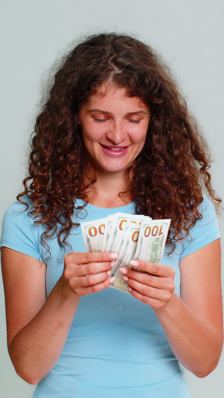 Donna che conta banconote in dollari, felicemente soddisfatta, celebrando risparmi salariali e guadagni finanziari
