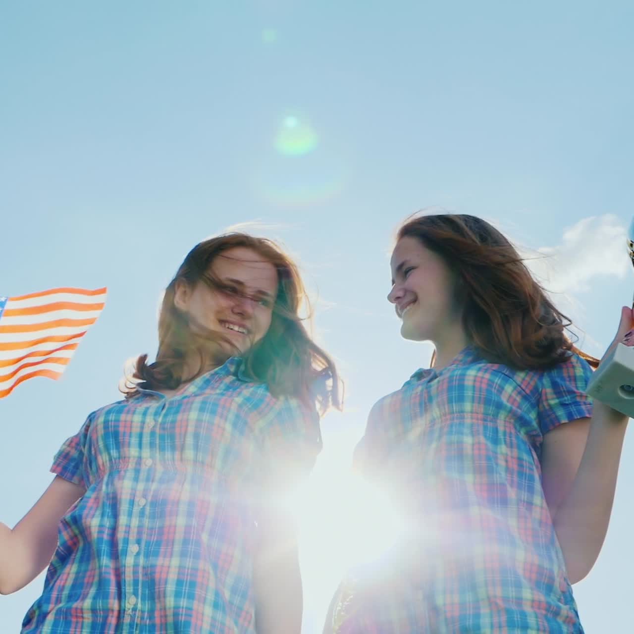 dos gemelas adolescentes con una copa de ganador y una bandera americana