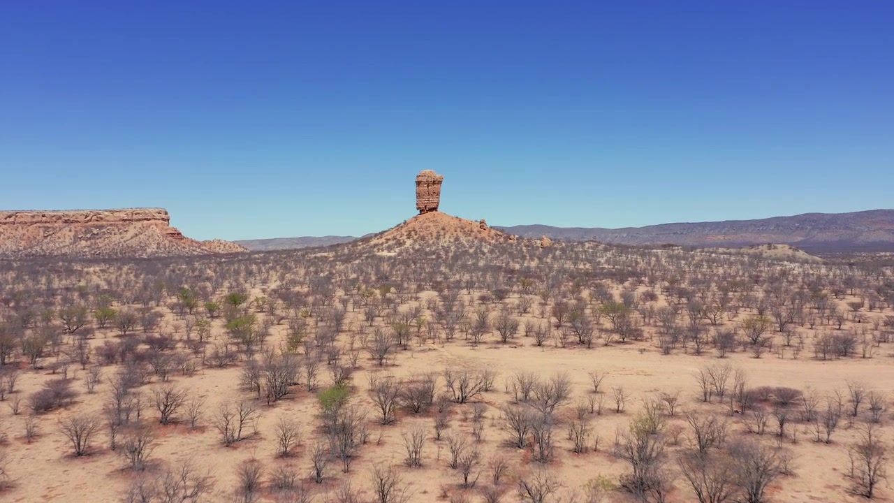 Aerial approach to Vingerklip rock formation rising above Ugab Valley in Namibia, drone dolly centered on monument