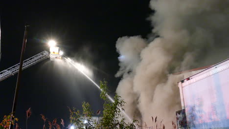 firefighters extinguish a fire from a crane with water with thick smoke