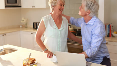 Senior-woman-giving-tea-to-senior-woman-in-kitchen