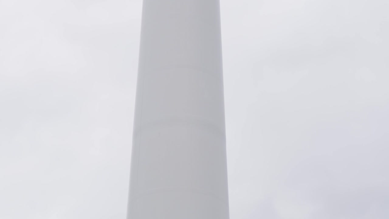 Shot of a wind farm turbine, its blades, the tower and the base