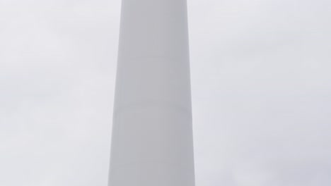 shot of a wind farm turbine, its blades, the tower and the base