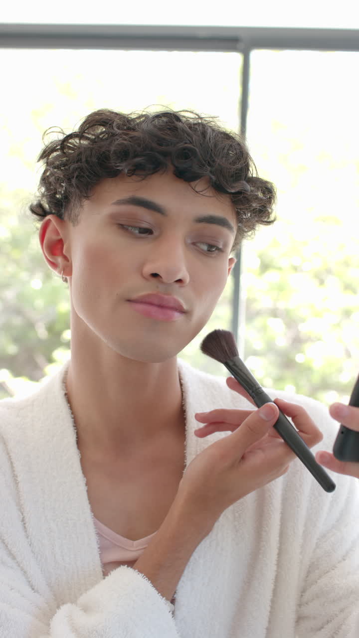 Vertical video: Applying makeup at home, young person using brush and smartphone mirror