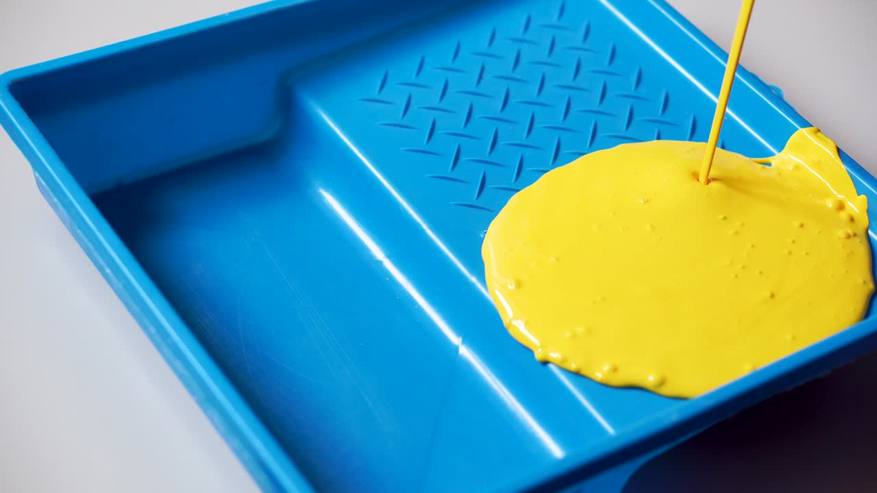 yellow paint is poured into a blue container