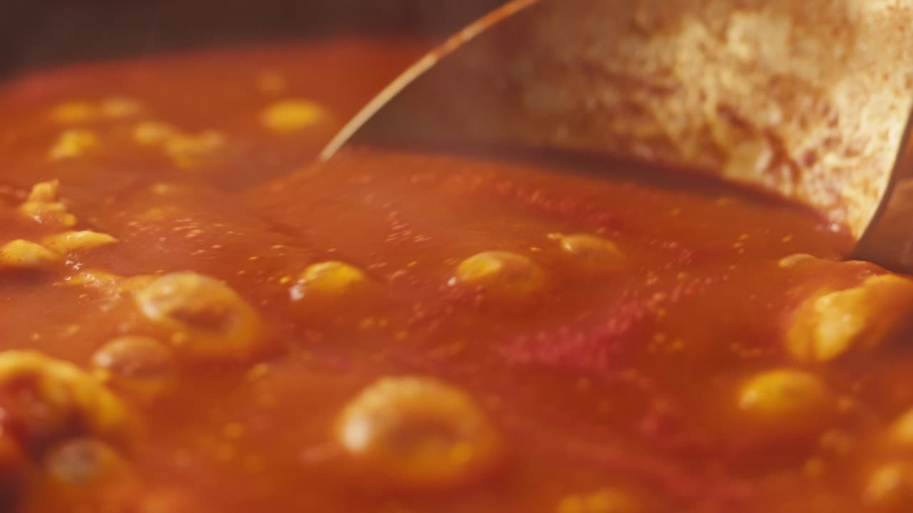 Chicken in tomato sauce is boiling on a frying pan with spices. Cooking tomato sauce curry with chicken fillet. Traditional Italian Mexican Asian dish. High quality studio shot for cafe, restaurant close up.