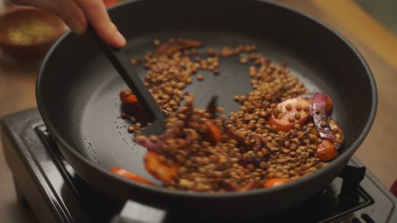 Crop cook frying vegetables with lentils