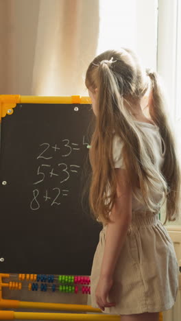 elder sister and little brother play school. girl teaches math lesson to preschooler brother. boy raises hand knowing answer and schoolgirl writes on blackboard