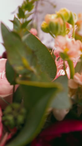 fresh bouquet with aromatic pink and purple flowers and small green leaves on white table extreme close view slow motion. florist service