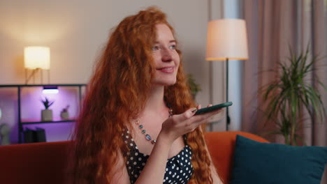 mujer de cabello rojo disfrutando de una llamada de teléfono inteligente hablando, conversación por teléfono móvil con amigos en casa