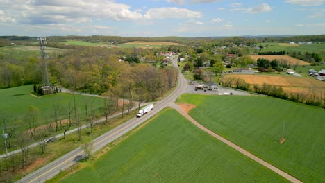 A-truck-backing-up-along-a-road-with-lush-green-grass-during-the-daytime