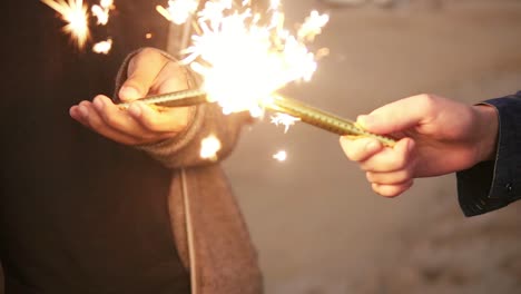 Close-Up-view-of-hands-of-friends-holding-sparkling-candles-and-lightning-them-up