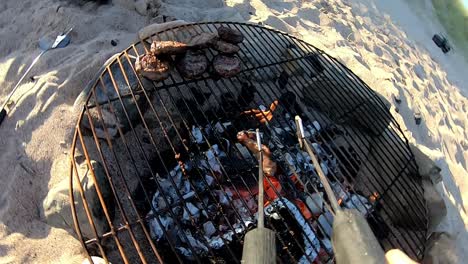 point of view shot of multi-generation family having evening barbecue around fire on beach vacation