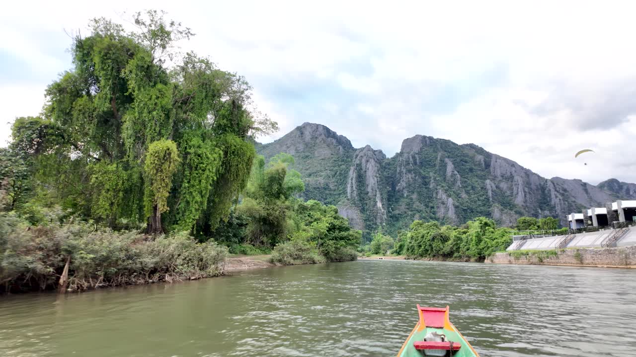 Peaceful Laos landscape with a colorful longtail boat on the Nam Song river near lush mountains