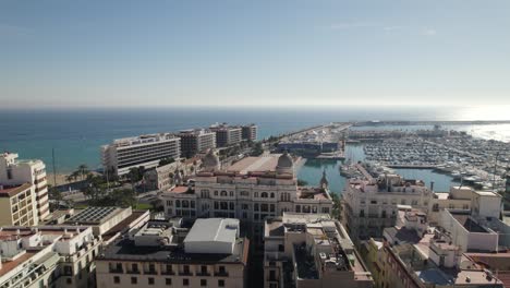 aerial towards alicante marina flyover downtown buildings, by mediterranean sea