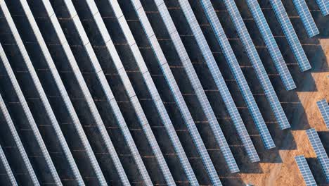 rows of photovoltaic solar panels in a field at a solar power plant. ecological production of electricity. top view shot by drone