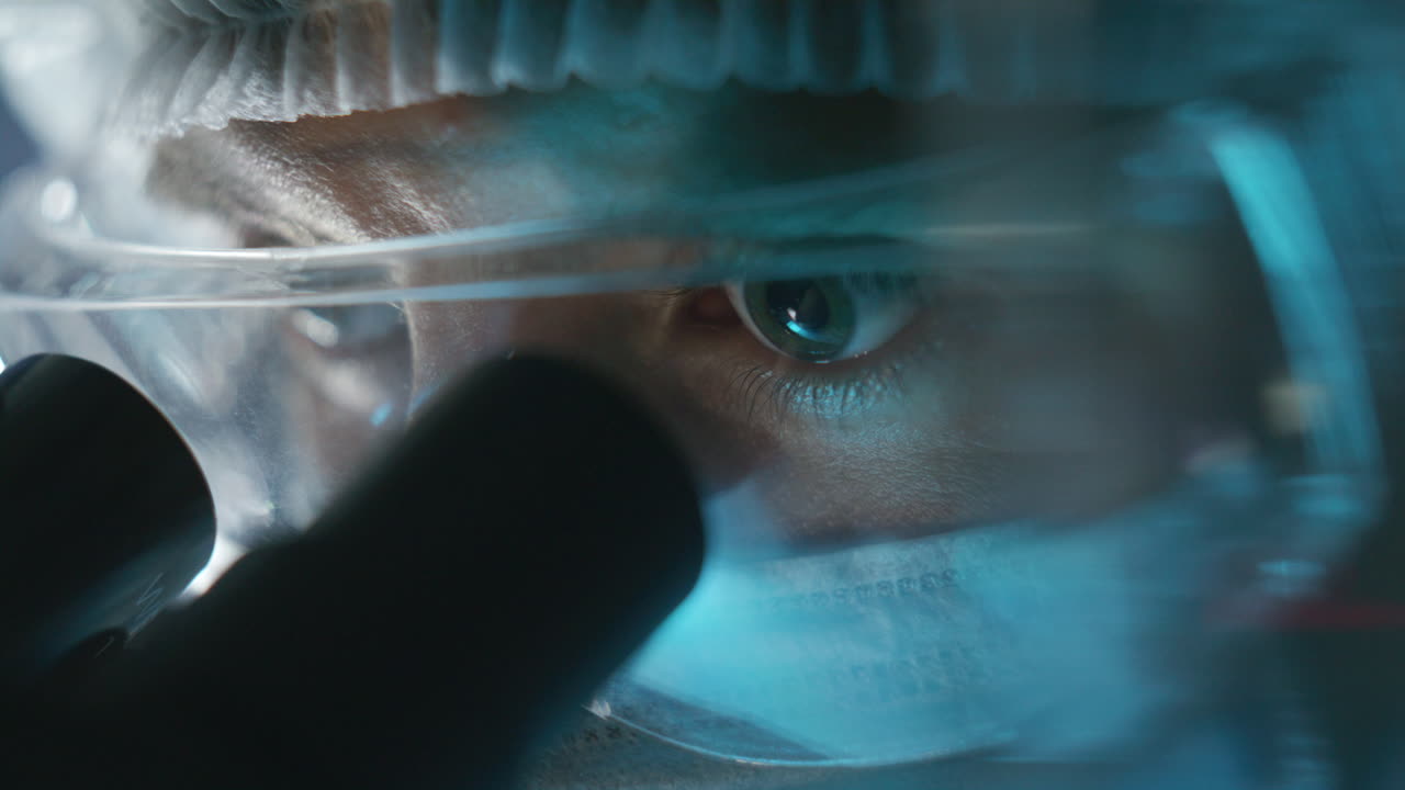 Concentrated Scientist Observing Sample through Microscope in Laboratory