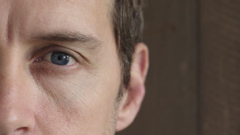 half-face-portrait-close-up-of-caucasian-man-blue-eye-looking-at-camera-on-wooden-background