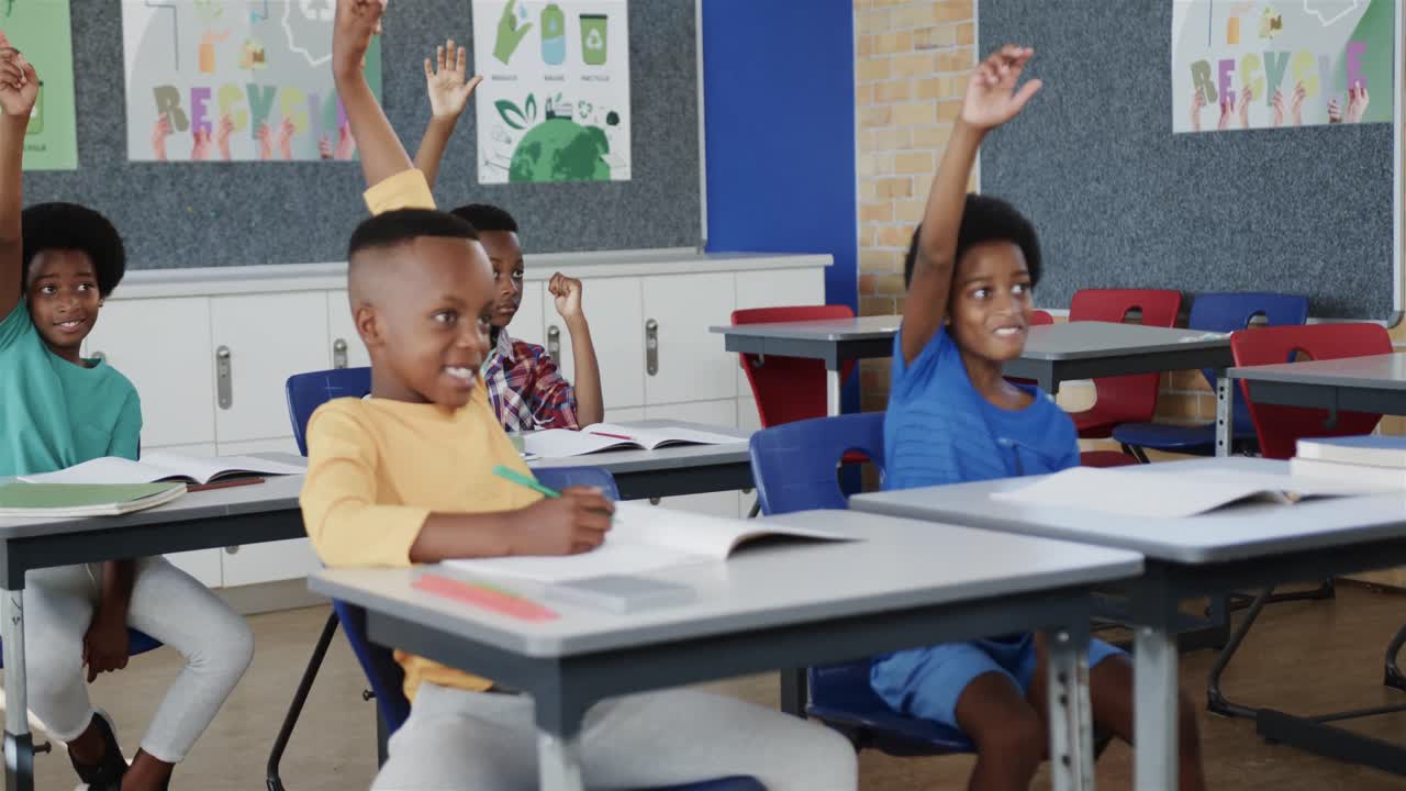 Happy diverse schoolchildren at desks raising hands in elementary school classroom in slow motion