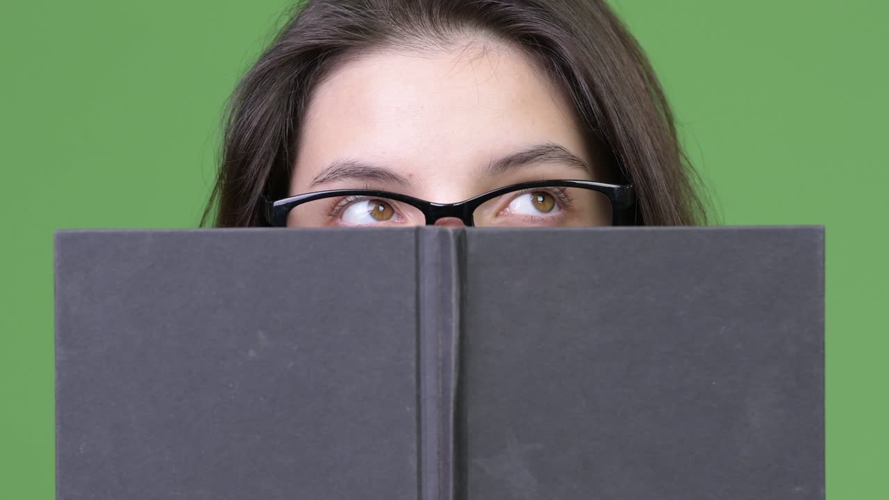 Young beautiful woman thinking while hiding behind book