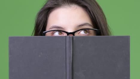 young beautiful woman thinking while hiding behind book