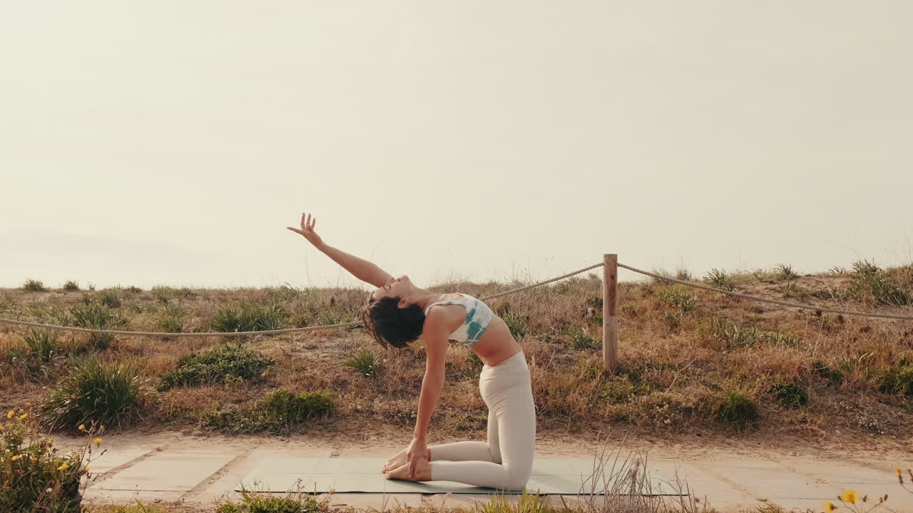 Donna che esegue la posa del cammello yoga su tappetino all'aperto