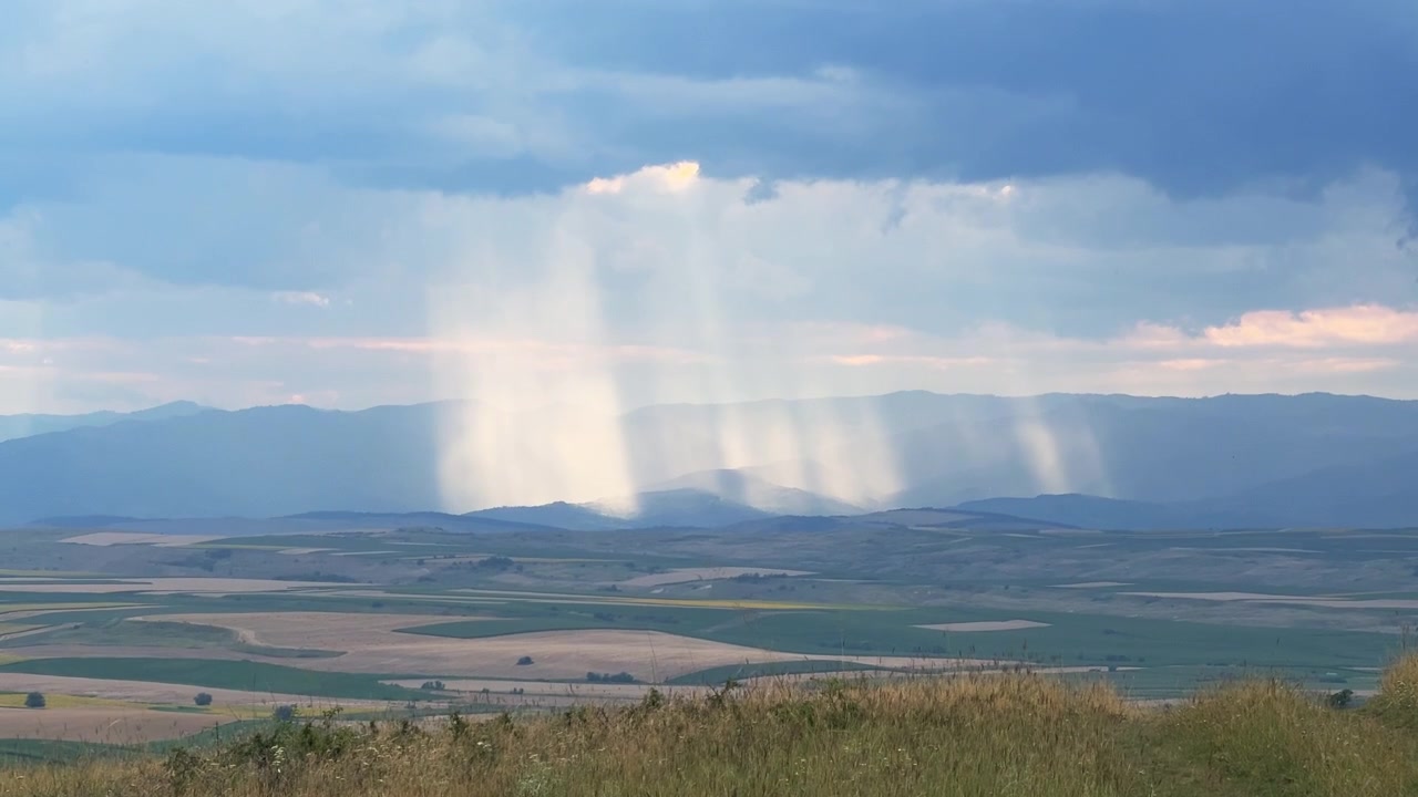 4K Dramatic Summer Storm Clouds with Rain Shaft and Sunbeams Over Landscape