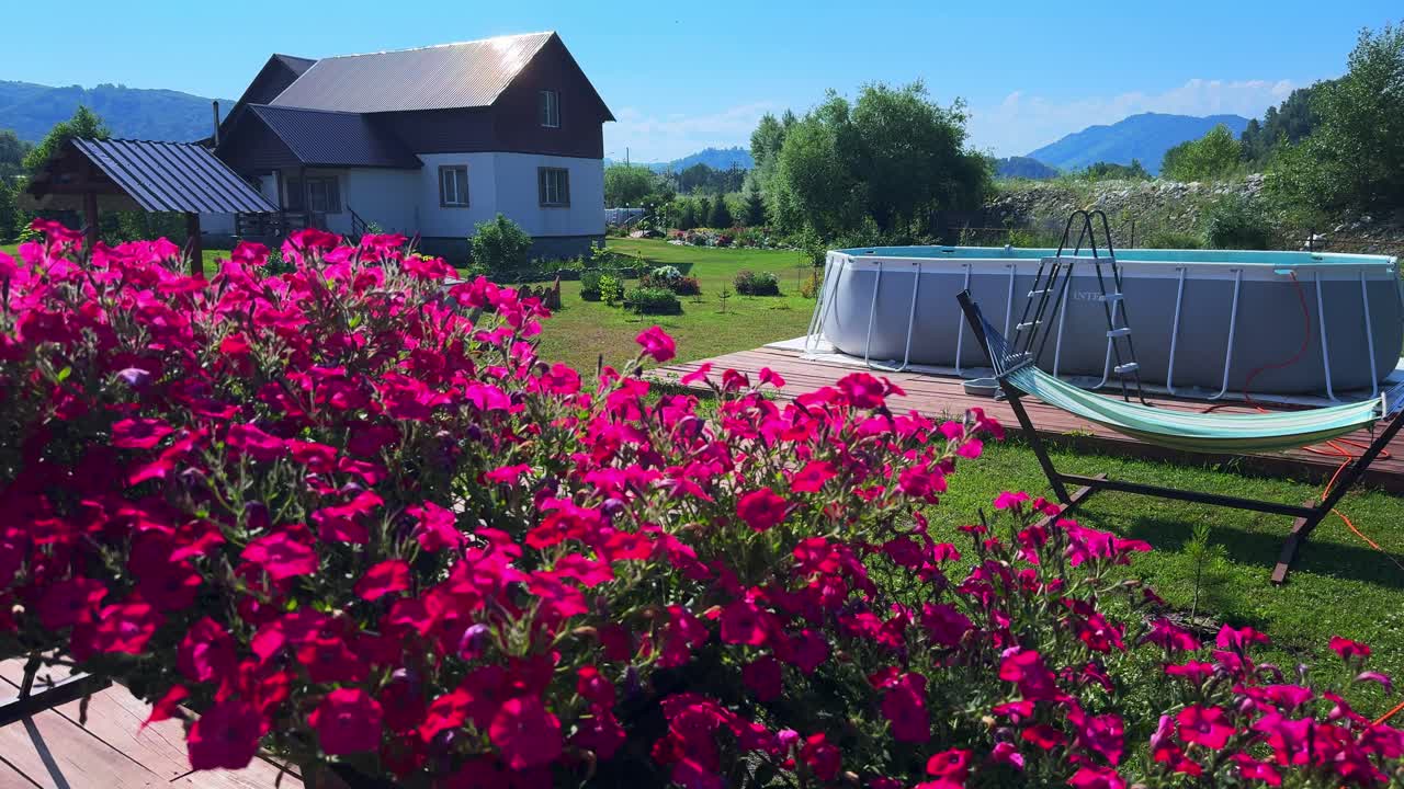 A Serene Rural Landscape Featuring Lush Pink Flowers and a Refreshing Pool Surrounded by Verdant Greenery and Scenic Mountains in the Background