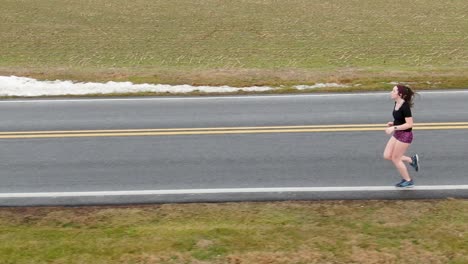 good mental health theme preventing depression, anxiety, suicide. young woman jogger enters frame, slow motion tracking shot features proper running form.