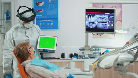 dentist with face shield pointing at green screen display