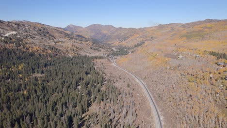 Toma-Aérea-Abierta-Que-Sigue-A-Lo-Largo-De-Un-Valle-Y-Una-Carretera-A-Través-De-Utah-Durante-El-Día-De-Otoño.