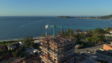 drone pans next to steel beams and concrete walls, with their shadows stretching toward shoreline’s evening shimmer. ideal for development or coastal contrast stories.penha - brazil