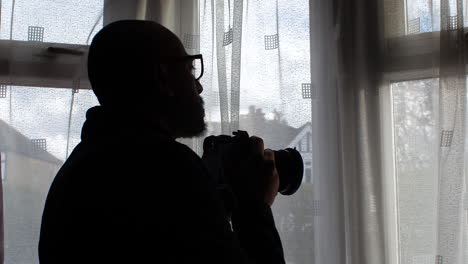 man taking picture with camera out of window at home - close up