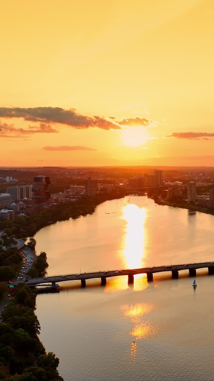 Amazing panorama of Boston, USA at sunset. Bright sun reflecting in the Charles River. Orange sky above the metropolis. Top view.. Vertical video