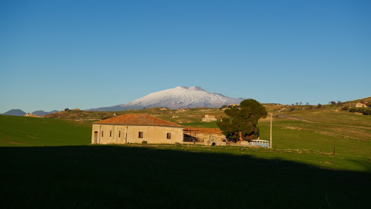 시칠리아의 황금시, 해가 지는 동안, 고귀한 에트나 산을 배경으로 한 집에 도착하는 향수를 불러일으키는 파란색 비.