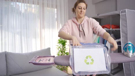 una mujer ecológica tira ropa al contenedor de reciclaje.