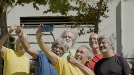 team of happy senior football players taking selfie on the soccer field