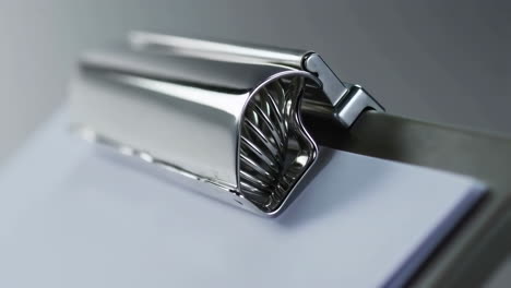 Close-up of a metal clipboard clip holding paper