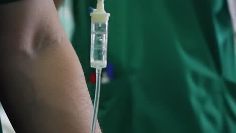 a patient receives intravenous treatment in a hospital room. the environment is calm and bright, with medical equipment visible in the background. attention is focused on patient care.