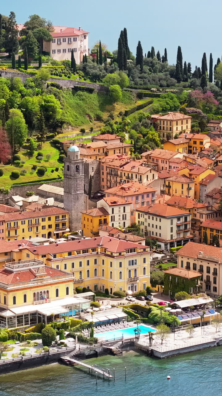Aerial drone view of the Basilica of St. Giacomo surrounded by houses in Bellagio, Italy. Vertical