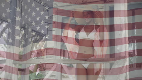 animation of american flag over happy african american woman wearing hat and bikini in the sun