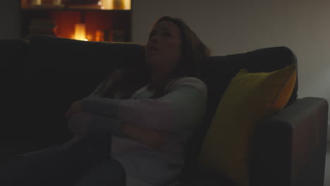 anxious or depressed woman sitting on sofa at home at night with lights turned off in the dark 1