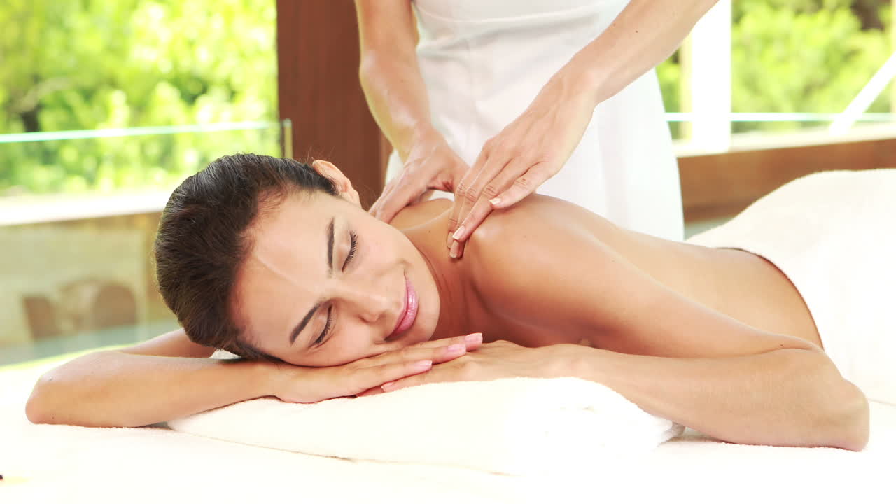 Massør giver massage til afslappende kvinde