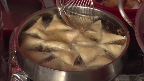 samboosa being deep fried in hot oil in a pan during bahrain's food festival