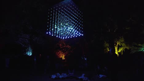 gente tumbada debajo de un cubo de luces colgantes.
