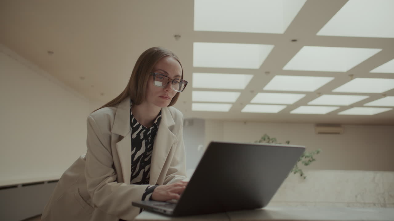 Donna d'affari concentrata che digita sul laptop in un moderno spazio ufficio