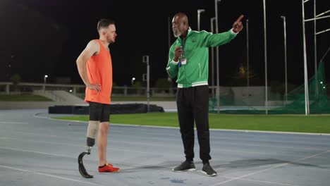 diverse male coach and disabled male athlete with running blade standing and talking