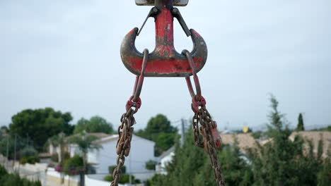 industrial chained crane hoist with weathered red paint lifting heavy goods